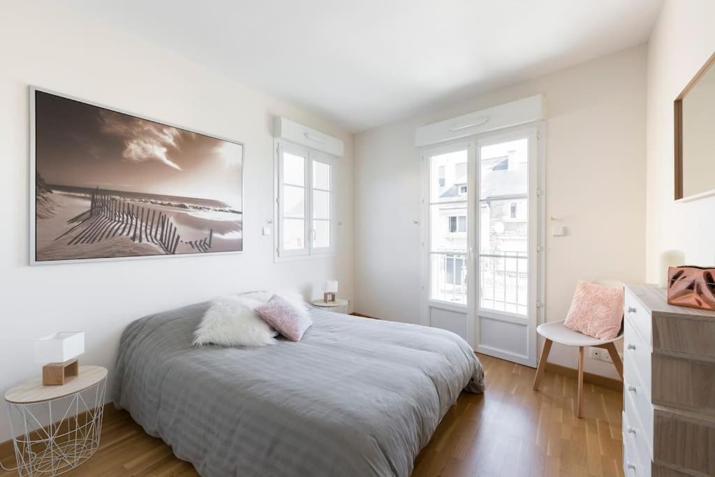 a white bedroom with a bed and two windows at Sweet Apartment in Saint Malo