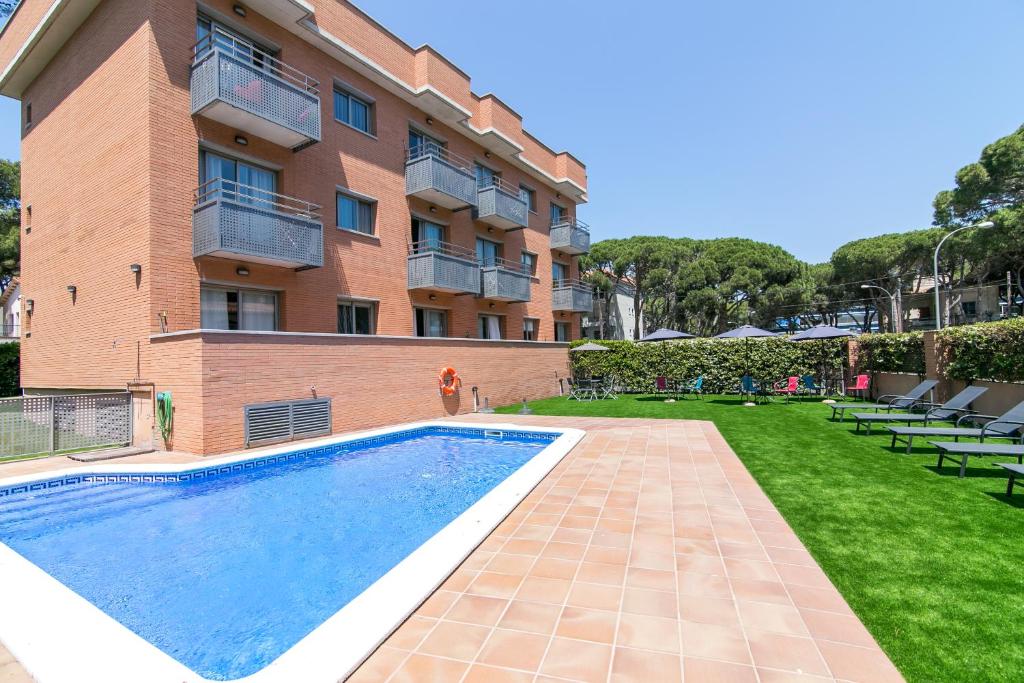 a swimming pool in front of a building at Aparthotel Bardon in Castelldefels