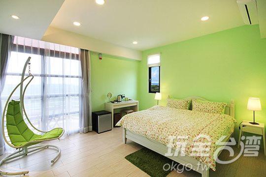 a green bedroom with a bed and a chair at Sea People B&B in Magong