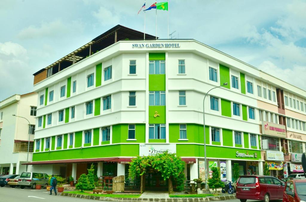 ein weißes und grünes Gebäude mit einer Flagge oben in der Unterkunft Swan Garden Hotel in Pasir Gudang