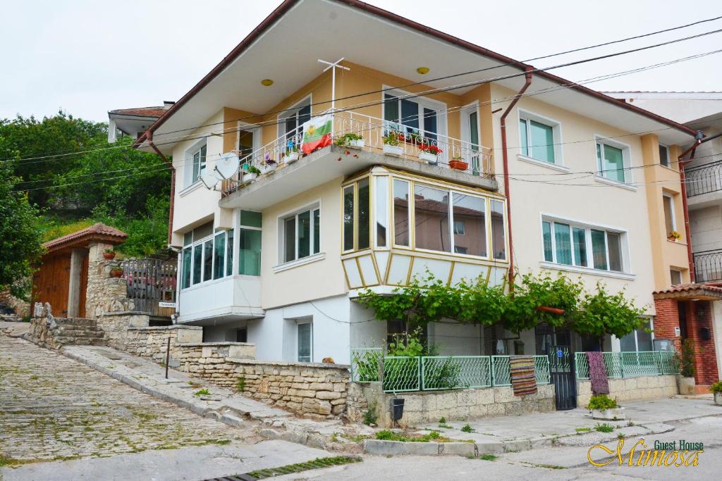 uma casa branca com uma varanda numa rua em Guest House Mimosa em Balchik