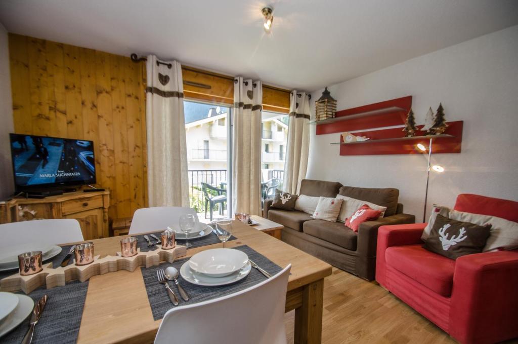 uma sala de estar com uma mesa e uma cadeira vermelha em Litchi Apartment em Chamonix-Mont-Blanc