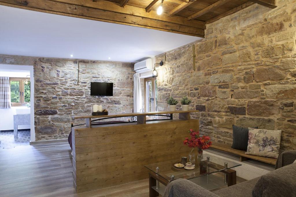 a living room with a stone wall at Voulamandis House in Kambos