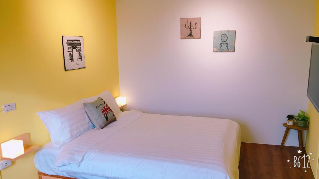 a small bedroom with a white bed and two pictures on the wall at 雲在山房 in Jiufen