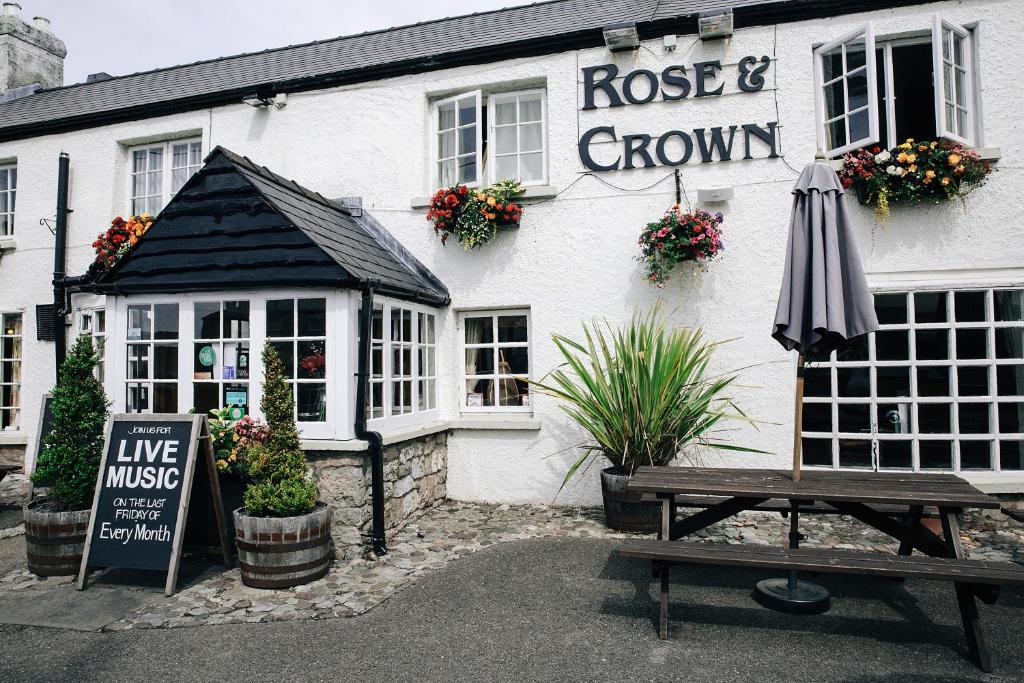 a building with a table and an umbrella in front of it at Rose And Crown in Porthcawl