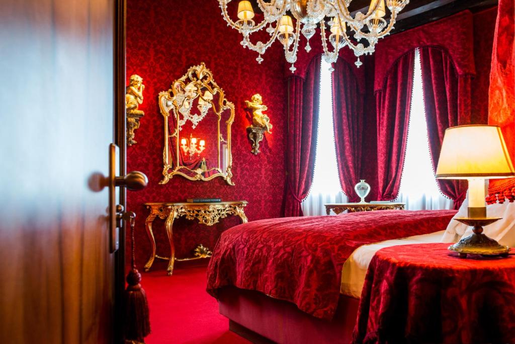 a red bedroom with a bed and a chandelier at Ca Maria Adele in Venice