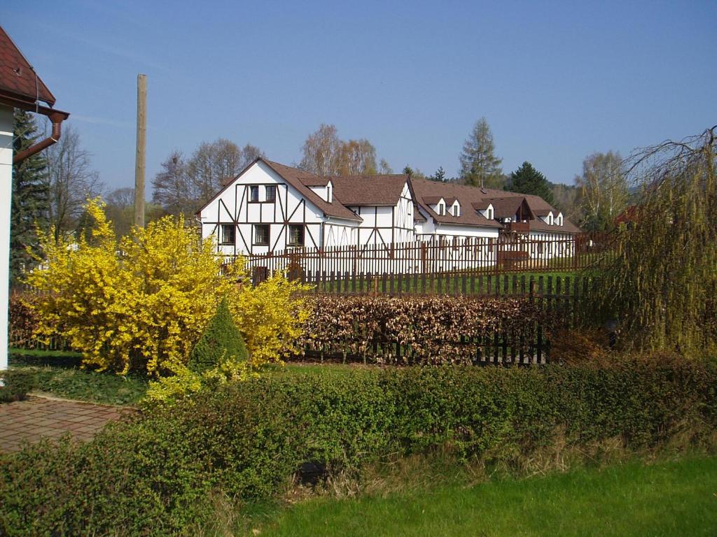 a large white house with a fence in front of it at Restaurace a Penzion Česká Hospoda in Heřmanice