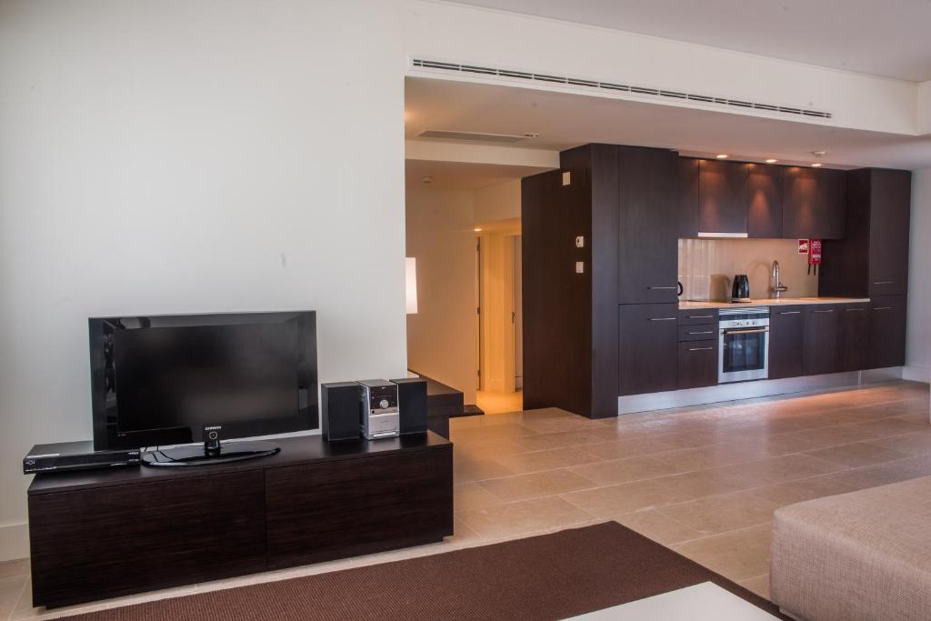 a living room with a flat screen tv and a kitchen at Troia Residence by The Editory - Apartamentos Marina in Troia