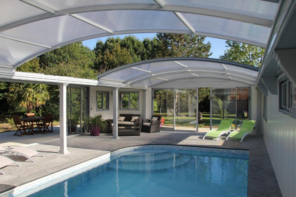 un patio avec une piscine et une pergola extensible dans l'établissement La Roulotte du Domaine de Meigné, à Meigné