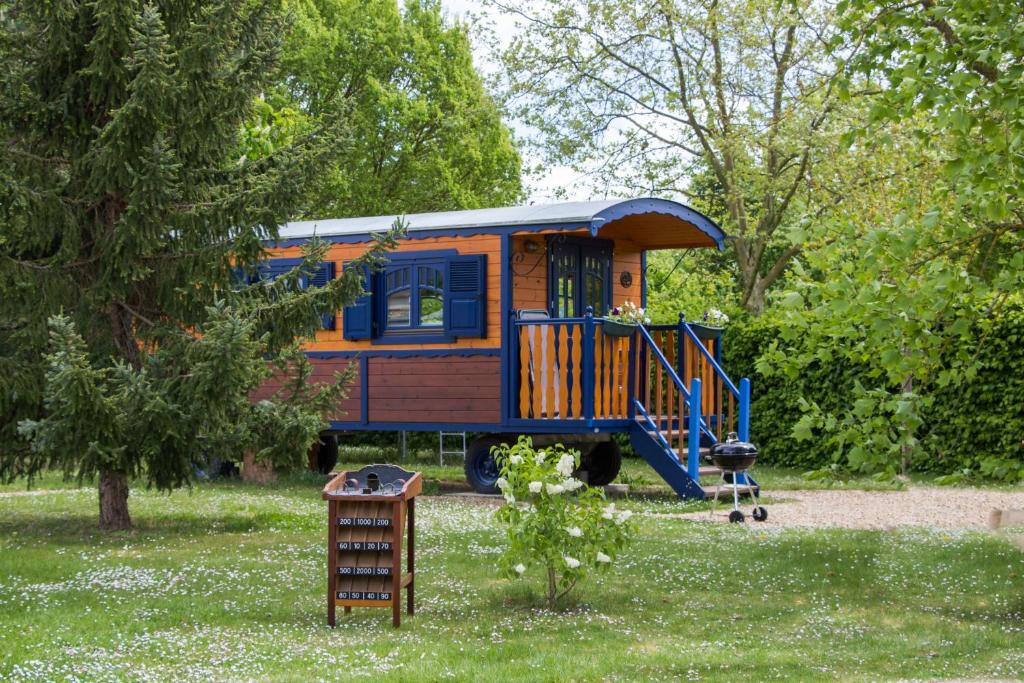 une voiture de train orange et bleue garée dans une cour dans l'établissement La Roulotte du Domaine de Meigné, à Meigné