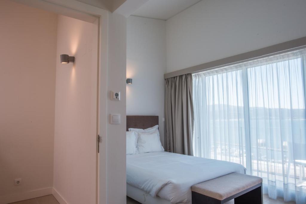 a bedroom with a bed and a large window at Troia Residence by The Editory - Apartamentos Marina in Troia
