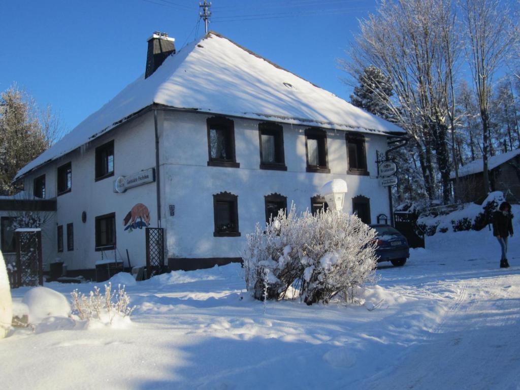 a white building with a snow covered roof at Pension Fuchsbau in Münchberg