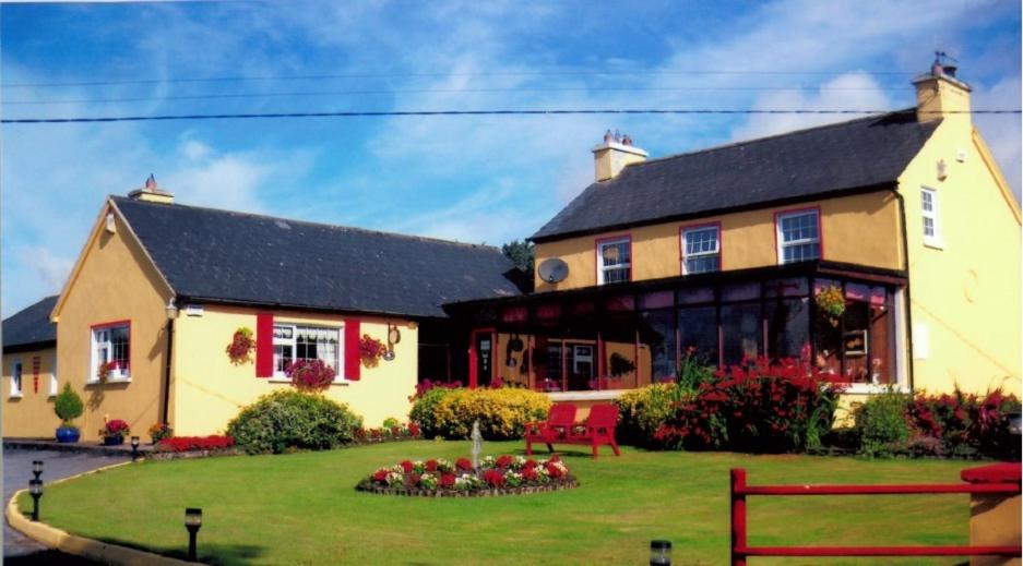 a large yellow house with a garden in front of it at Findus House, Farmhouse Bed & Breakfast in Macroom