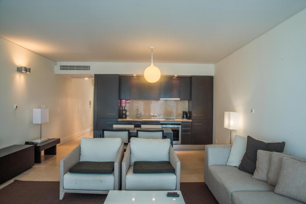 a living room with a couch and chairs and a kitchen at Troia Residence by The Editory - Apartamentos Marina in Troia