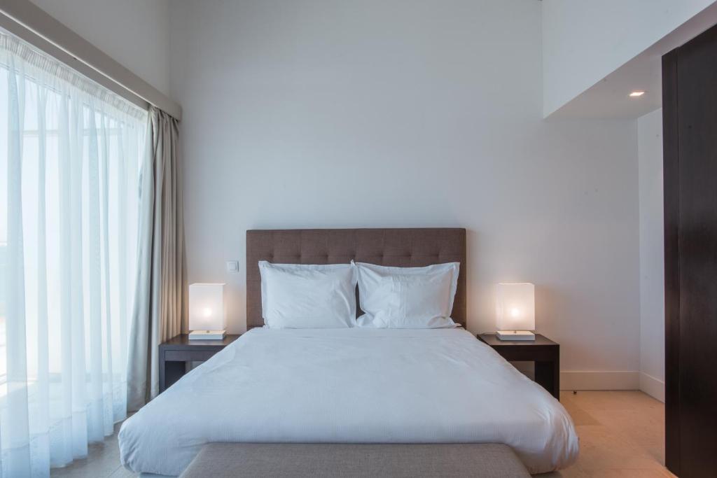 a bedroom with a large bed with two lamps on tables at Troia Residence by The Editory - Apartamentos Marina in Troia