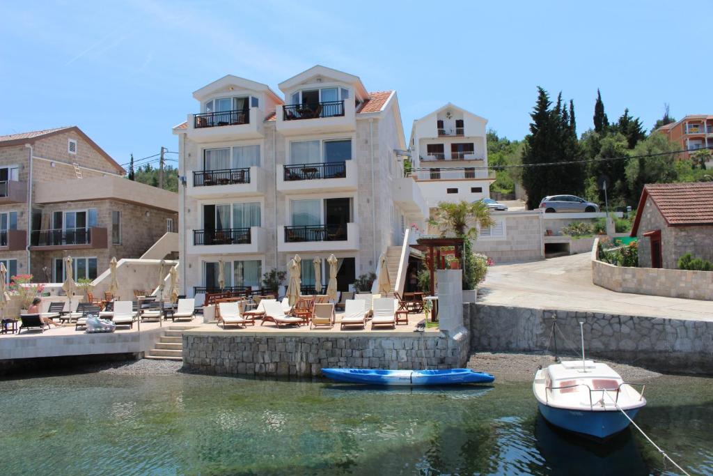 een groot huis met een boot in het water bij Apartments Harmonia in Tivat