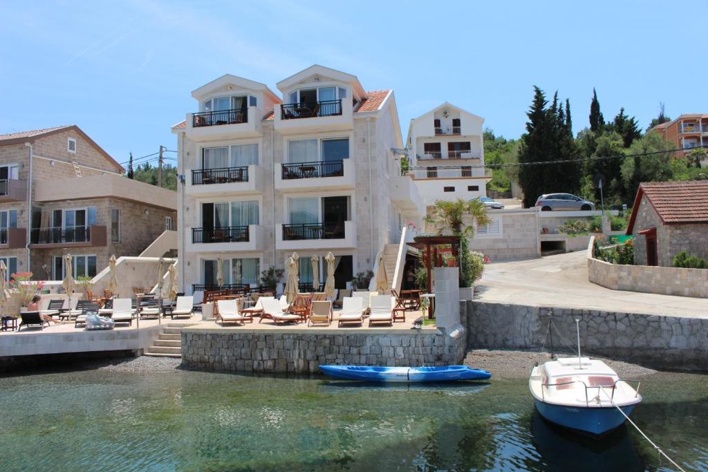 a large house with a boat in the water at Apartments Harmonia in Tivat