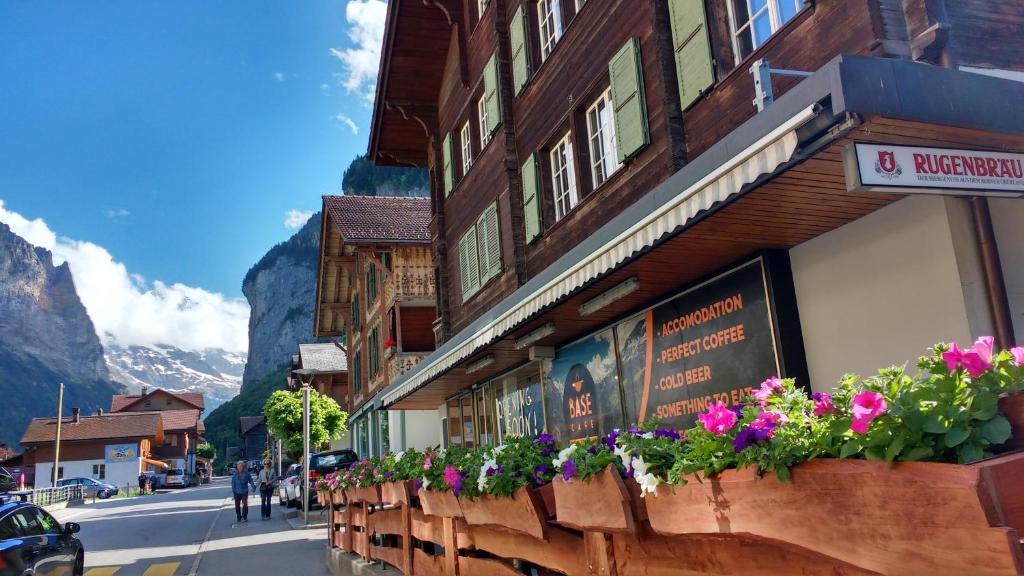 um edifício com flores ao lado de uma rua em BASE Cafe em Lauterbrunnen