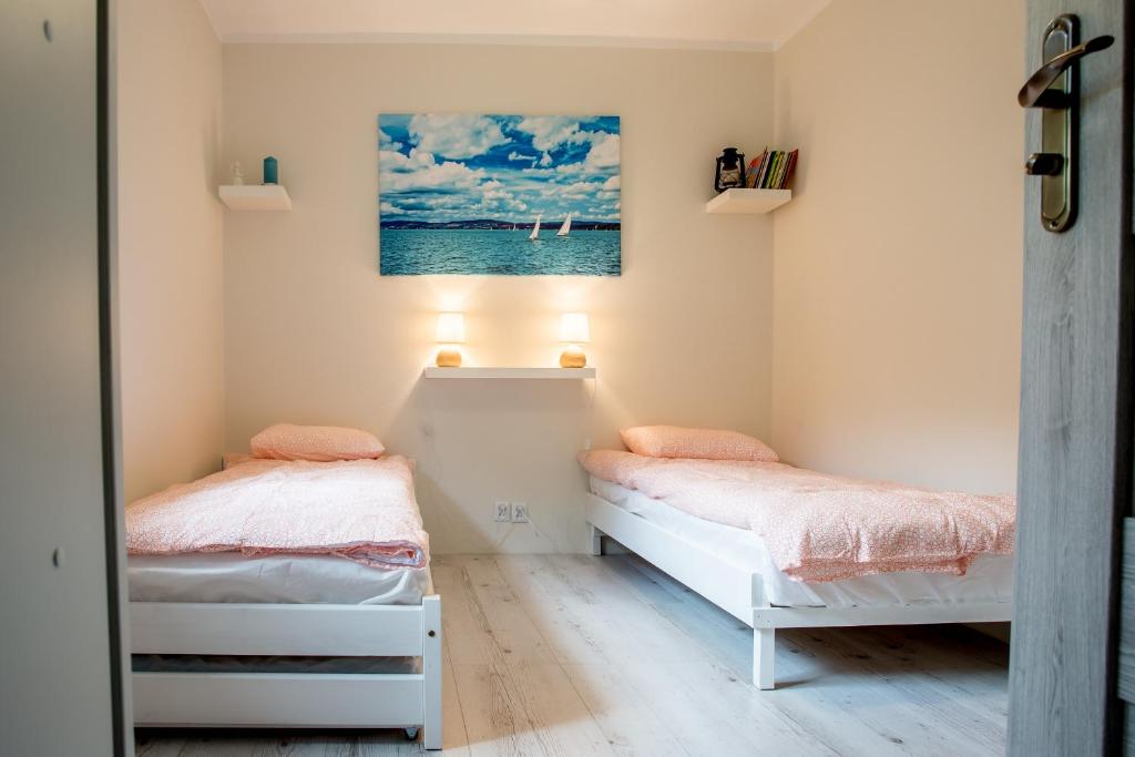 a bedroom with two beds and a painting on the wall at Apartament Mrągowo in Mrągowo