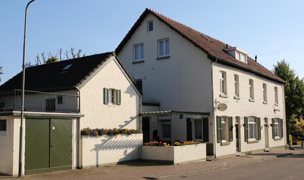 uma grande casa branca com uma garagem verde em Walnut Lodge Bed & Breakfast em Noorbeek