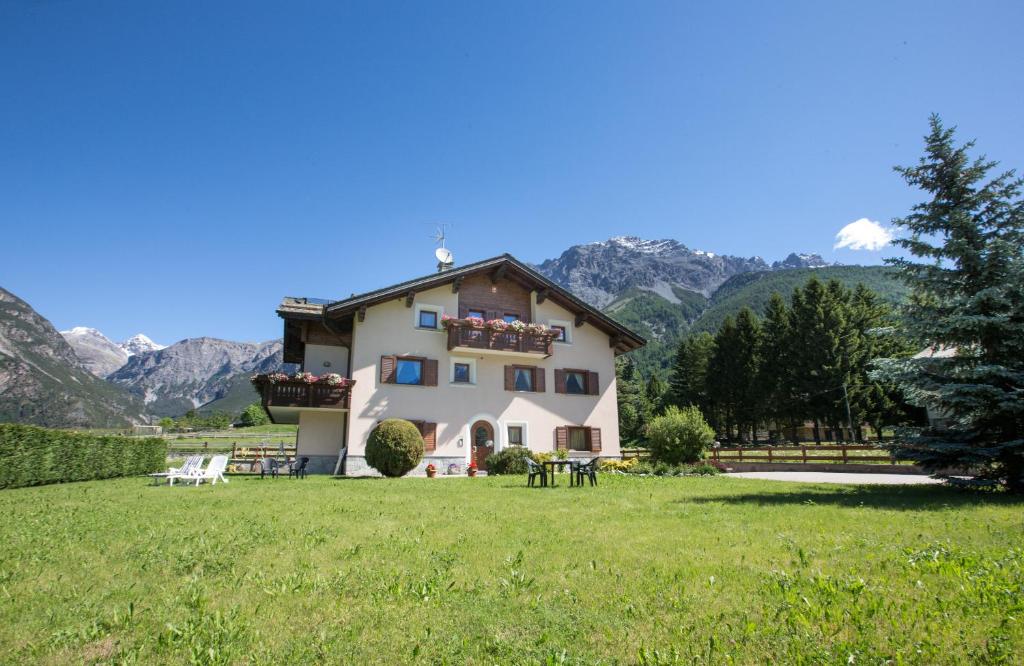 a house in a field with mountains in the background at Casa Margherita in Bormio