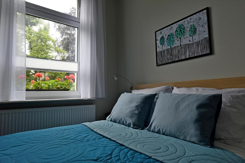 a bedroom with a bed with blue sheets and two windows at Like at Home in Sopot