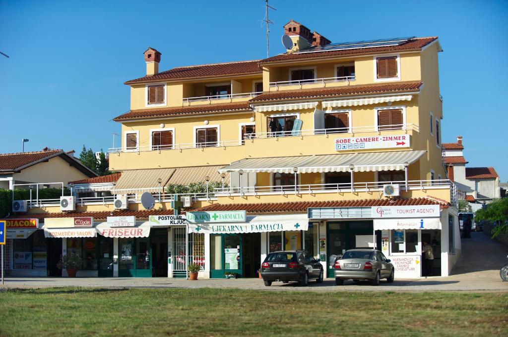 un grande edificio giallo con macchine parcheggiate di fronte di Pansion Valbruna a Rovigno (Rovinj)