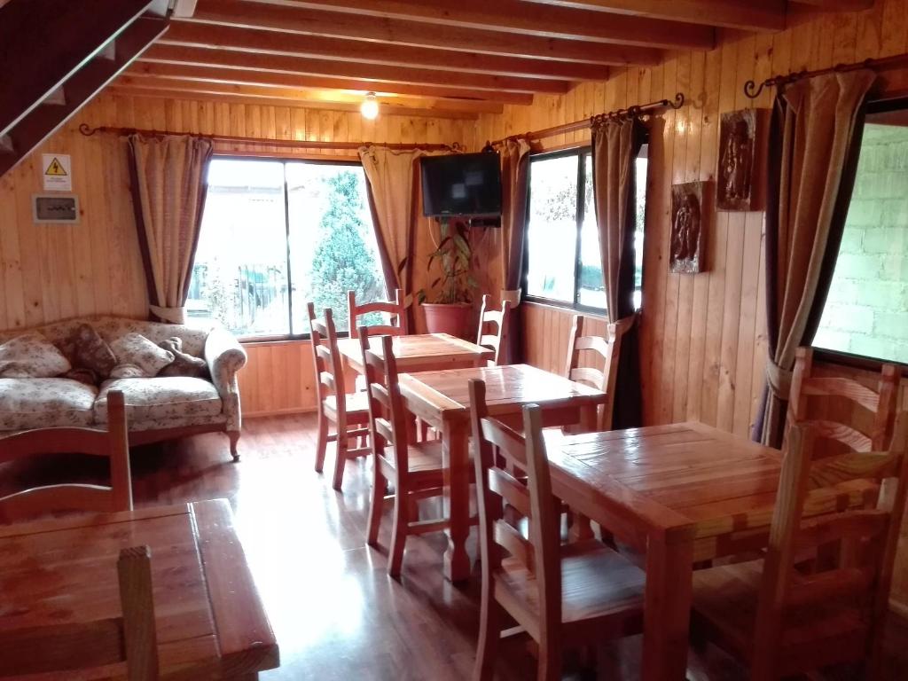 sala de estar con mesas, sillas y sofá en Hostal Monica, en Pucón