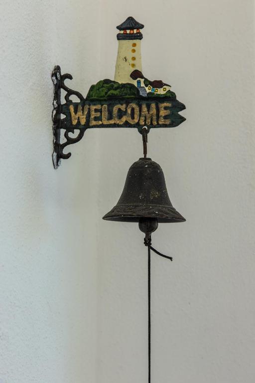 a welcome sign with a lighthouse on top of a bell at Villa il Poderino in Marina di Campo