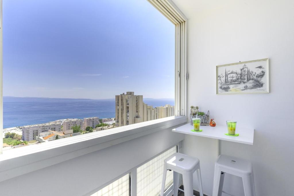 a white balcony with two stools and a large window at FM Apartments in Split