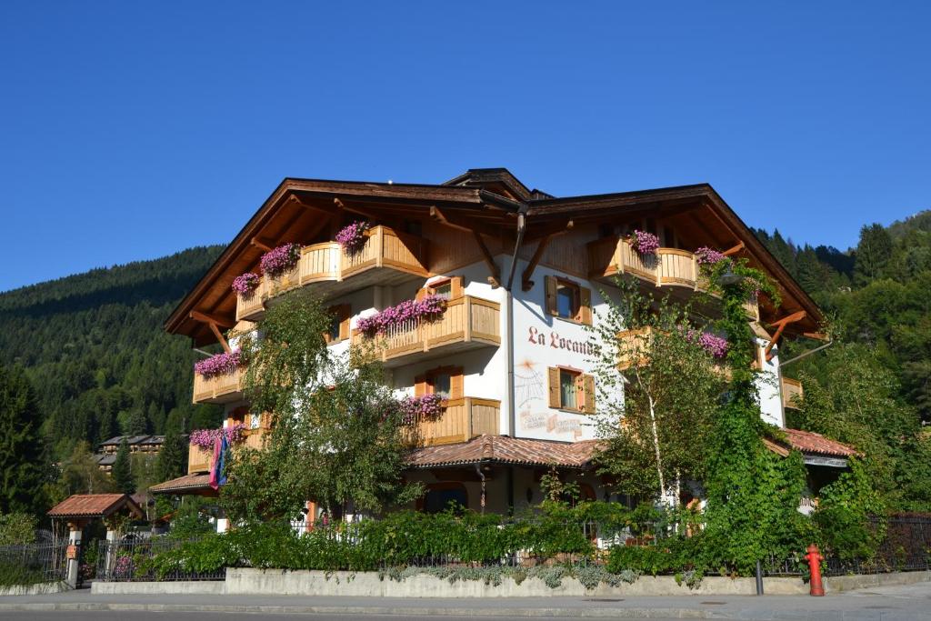 un edificio con dei fiori sul lato di HOTEL La Locanda a Pinzolo