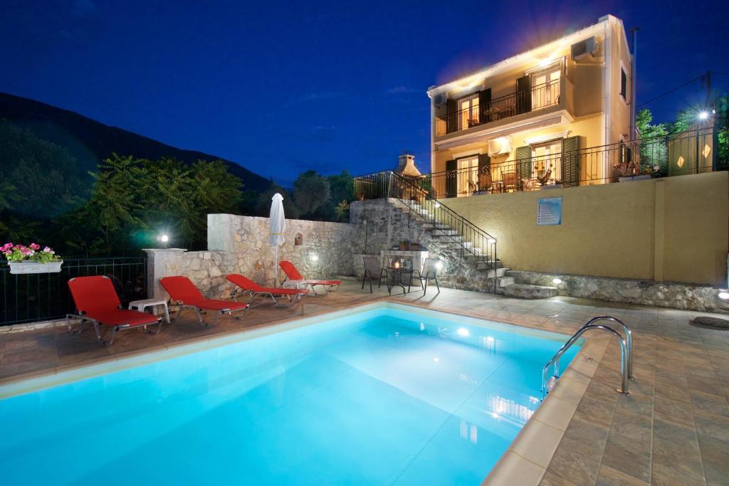 a swimming pool in front of a house at night at stunning tranquil villa with private pool in Sami
