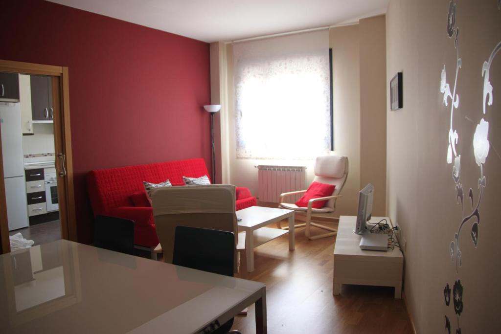 un soggiorno con divano rosso e tavolo di Alojamiento Losillas 2 ad Ávila