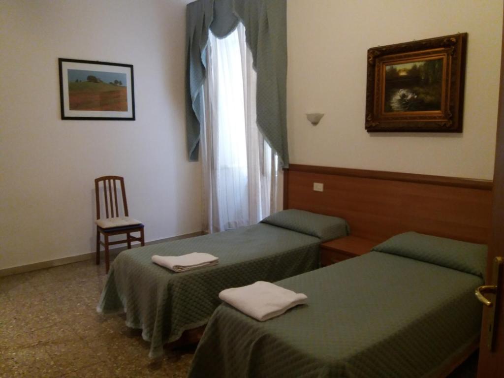ローマにあるRitmo Blues B&Bのベッド2台、椅子、窓が備わる客室です。