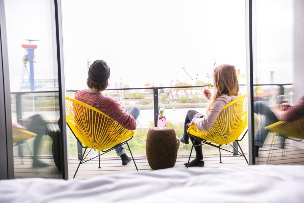 two women sitting in yellow chairs on a balcony at Hafenapartments Warnemünde in Warnemünde