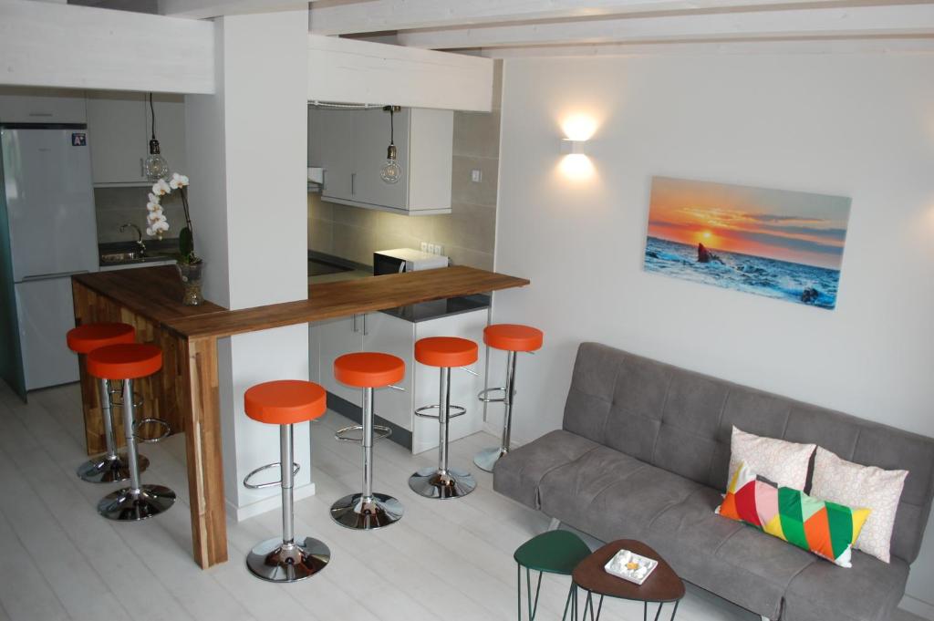 Sala de estar con sofá, mesa y taburetes en Apartamentos La Harinera, en Torres de Albarracín