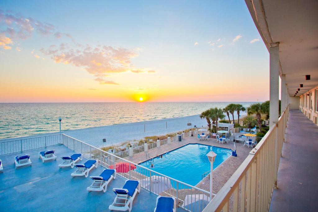 a view of a pool and the ocean at sunset at Beachside Resort Panama City Beach in Panama City Beach