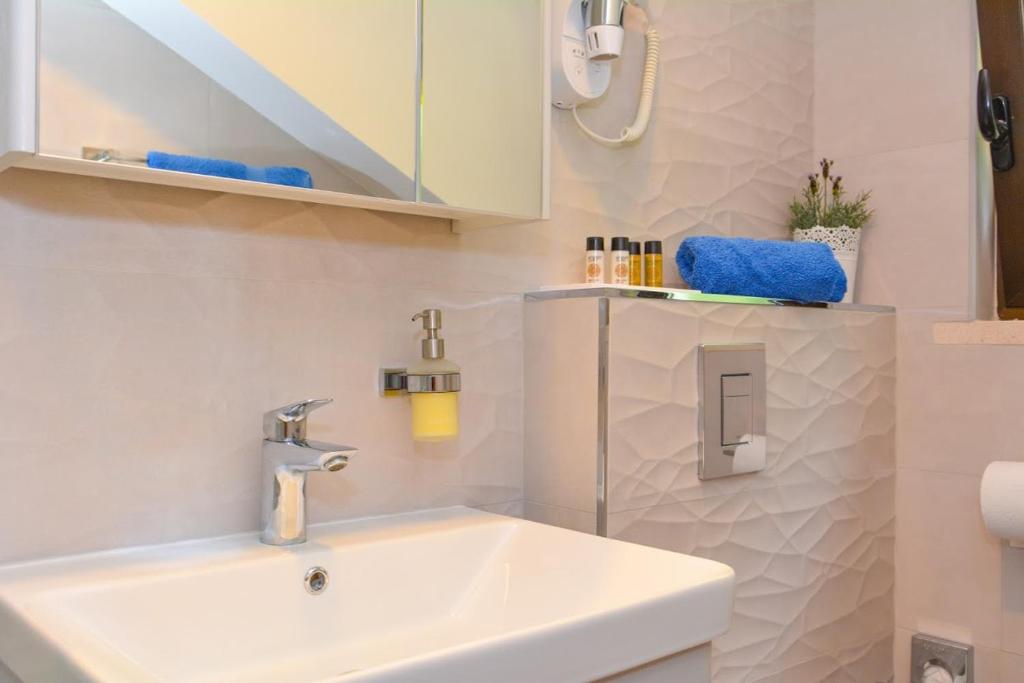 a white bathroom with a sink and a mirror at Apartment and room Sveti Jakov in Dubrovnik