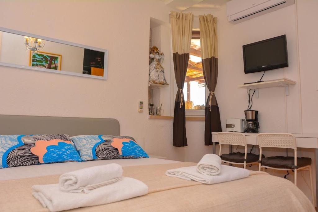 Apartment and room Sveti Jakov في دوبروفنيك: غرفة نوم بسرير وتلفزيون وطاولة