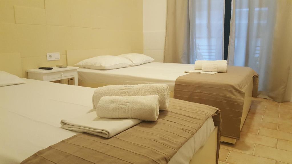 a room with two beds with folded towels on them at Enalio Rooms in Glida