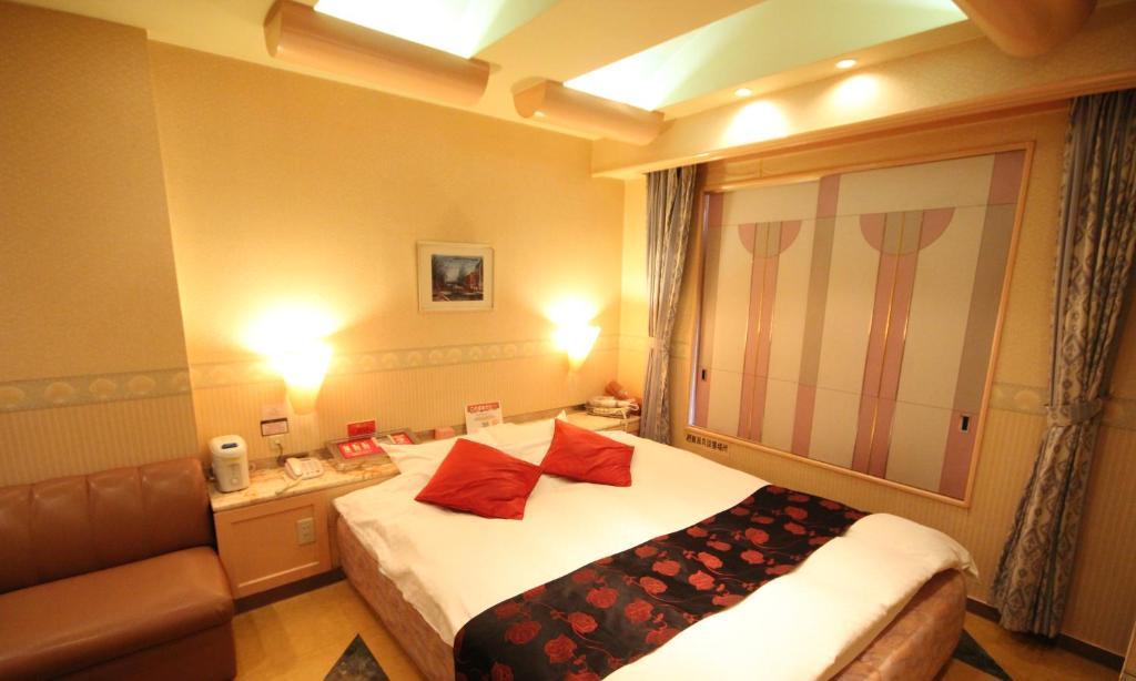 een hotelkamer met een bed met rode kussens erop bij Hotel Dressy (Adult Only) in Himeji