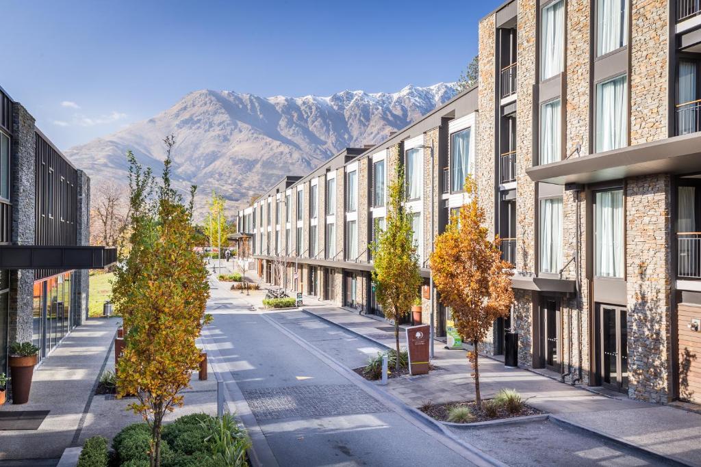 una calle vacía con edificios, árboles y montañas en DoubleTree by Hilton Queenstown en Queenstown