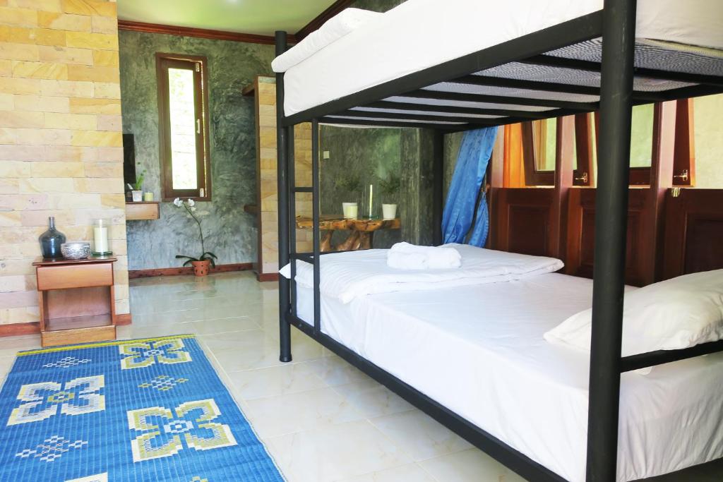 a bedroom with two bunk beds and a blue rug at Wonderland Healing Center in Thongsala