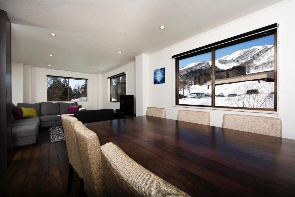 a living room with a large wooden table and a couch at Sky Park Happo Chalet in Hakuba