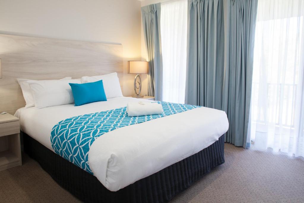 Habitación de hotel con cama grande con almohadas azules en Busselton Villas and Glamping Village, en Busselton