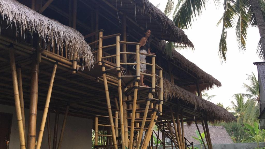 a man on a ladder on a straw building at Captain Coconuts Gili Air in Gili Air