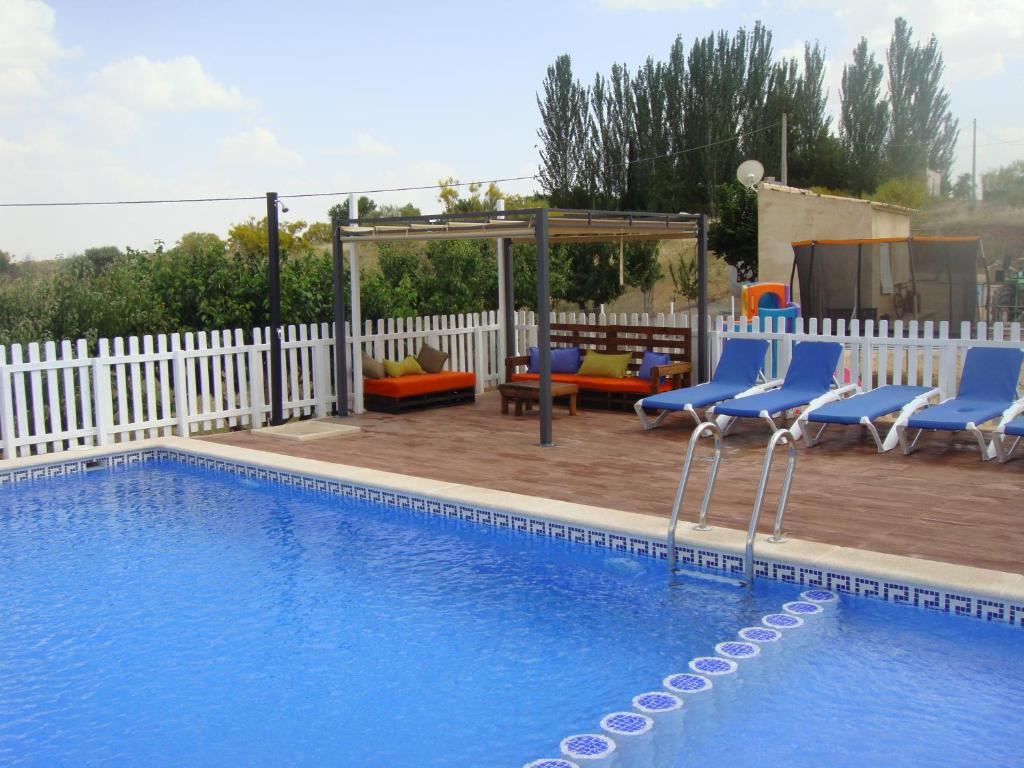 una piscina con sillas azules y un cenador en casa rural terron, en Alhambra
