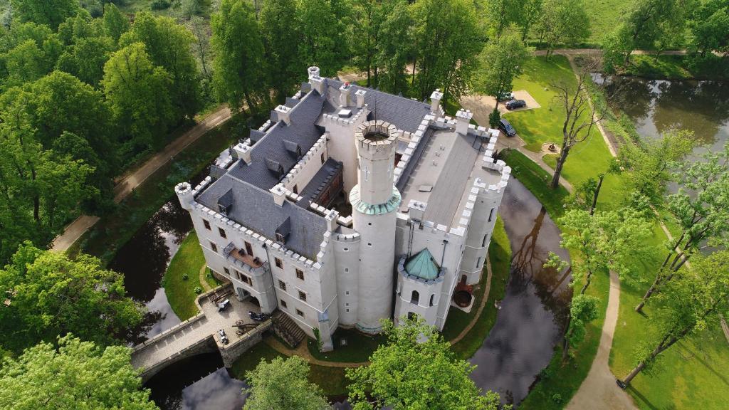 High-angle view of white castle surrounded by winding paths, moat and reflective ponds in verdant parkland