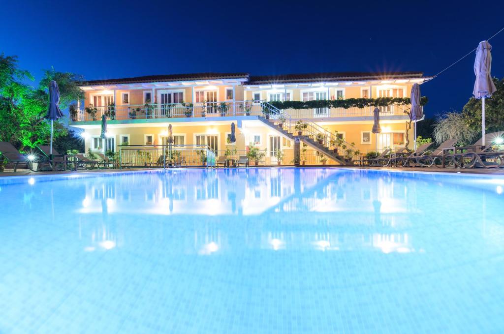 a large swimming pool in front of a building at night at Artemis Apartments in Kypseli
