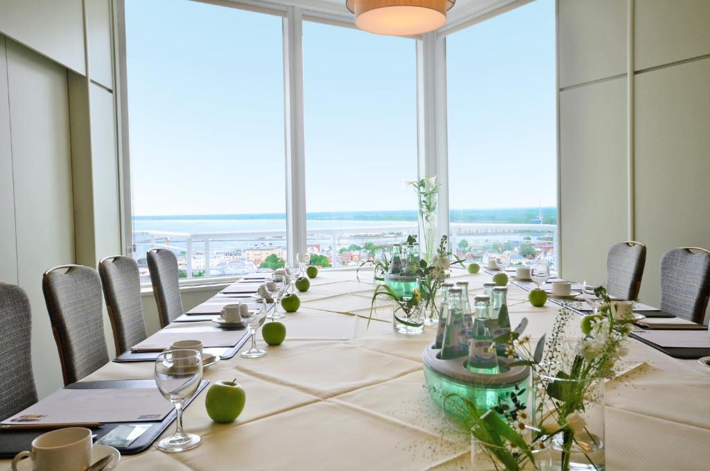 a long table in a room with large windows at Hotel Neptun in Warnemünde